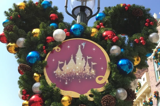 Décoration de Noël en forme de tête de Mickey, avec boules colorées et silhouette de château.
